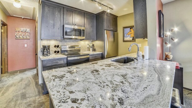 Una cocina moderna con gabinetes de madera oscura, electrodomésticos de acero inoxidable y una isla grande de mármol.