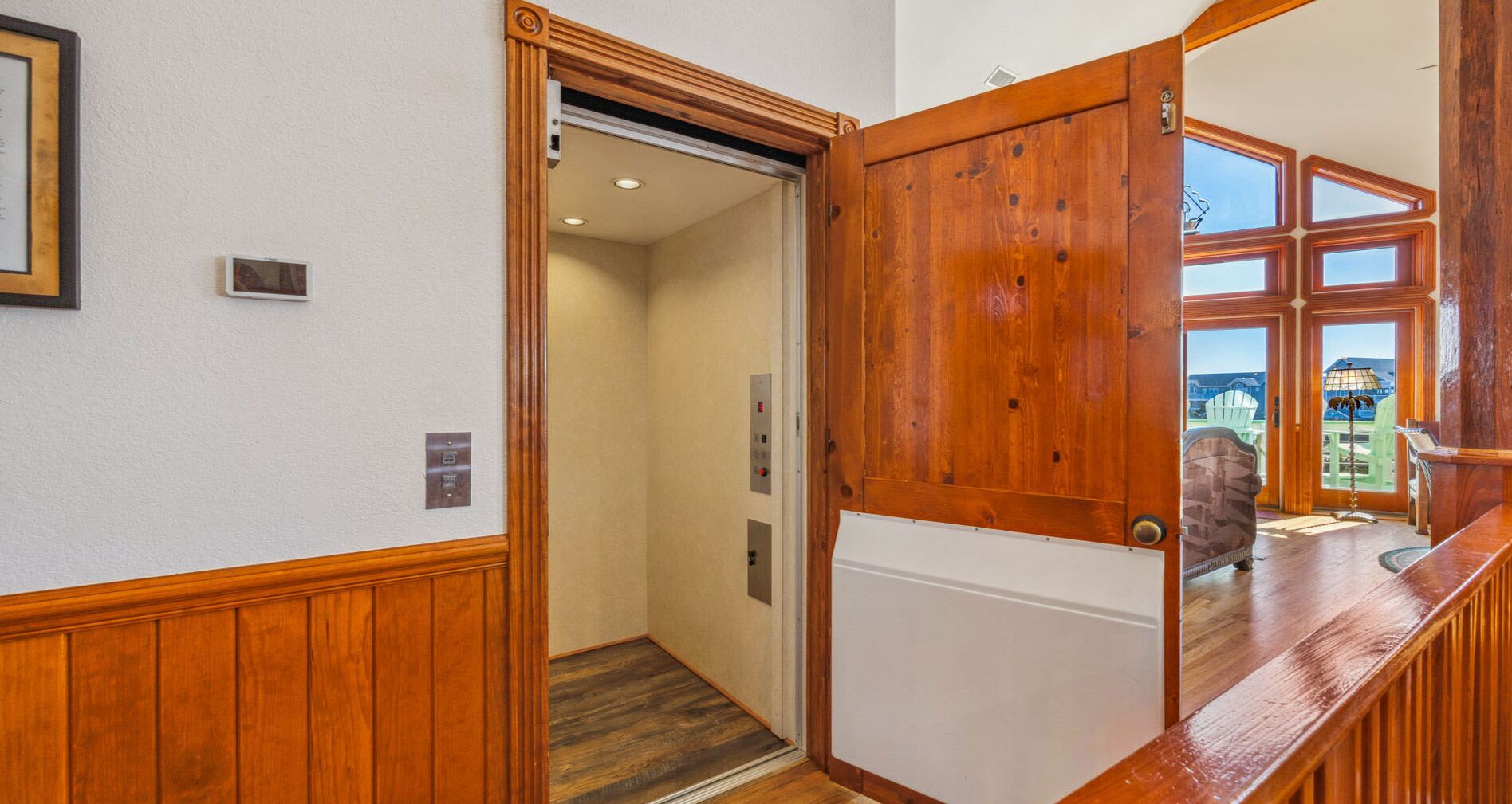 A wooden-framed elevator door with a view of a building outside.