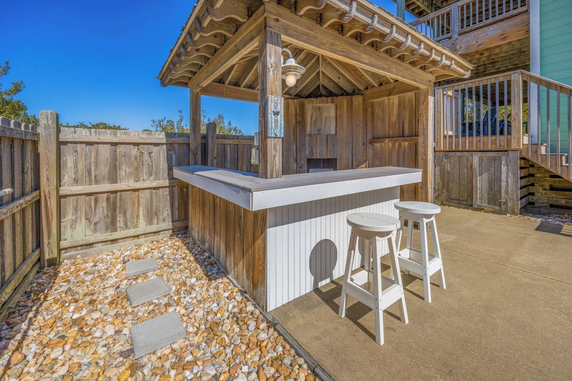 A wooden outdoor bar area with a counter and two stools.