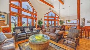 A spacious living room with leather sofas, a glass coffee table, and large windows offering a view of the city.