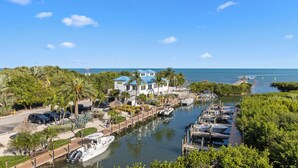 A marina with boats docked, a pathway leading to buildings, and a clear view of the water. - Ocean View 2BR Pool, Private Beach (Tavernier)