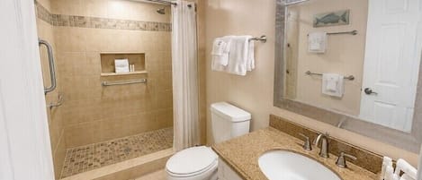 A bathroom with a shower, toilet, sink, and a mirror with a towel rack.