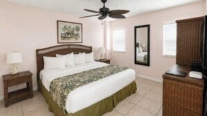 A bedroom with a bed, a nightstand, a dresser, a ceiling fan, and a wall-mounted mirror. - Ocean View 2BR Pool, Private Beach (Tavernier)