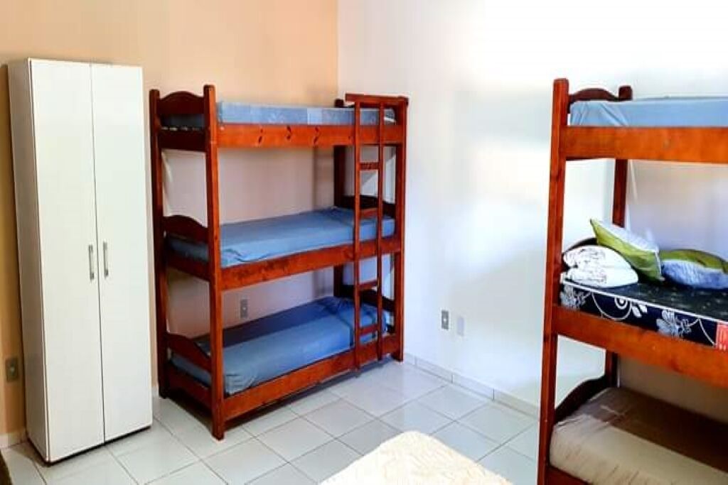 Quarto com beliches, um guarda-roupa e chão ladrilhado.