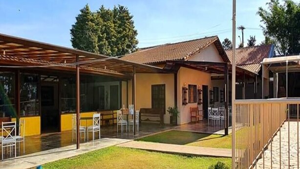 A covered outdoor area with a pool, seating, and a building with a tiled roof.