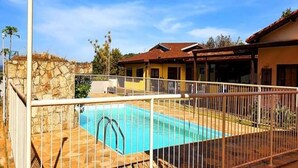 A swimming pool with a stone wall and a metal fence.