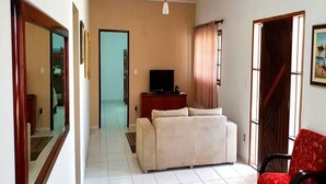 A living room with a sofa, a television, and a red chair.