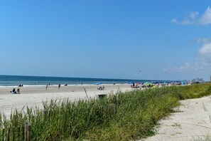 Una playa con gente, sombrillas y un cielo despejado.