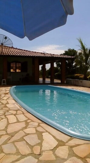 Relax by the pool surrounded by palm trees and a covered seating area.