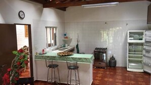 Una cocina con una isla central, taburetes de bar, estufa y refrigerador.