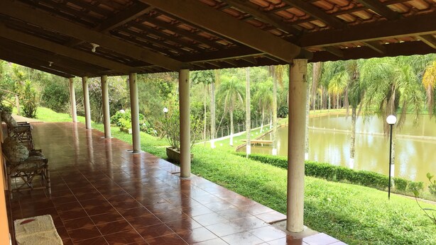 Un espacio al aire libre cubierto con suelo de baldosas, asientos y vistas a un estanque.