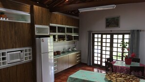 Una cocina con armarios de madera, un refrigerador blanco, un microondas y una mesa con mantel floreado.