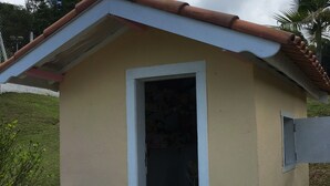 Un edificio pequeño de una sola planta con techo de tejas y una puerta que da a un espacio interior.