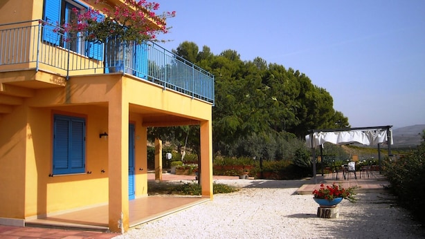 A yellow building with blue shutters and a balcony with pink flowers. - Cozy Studio Erato ideal for a couple (Menfi)