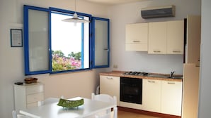 A compact kitchen with a dining table, chairs, a stove, and cabinets. - Cozy Studio Erato ideal for a couple (Menfi)