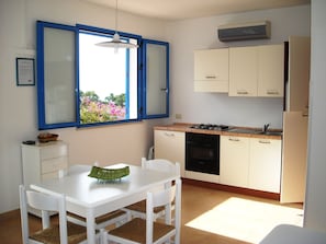 A compact kitchen with a dining table, chairs, a stove, and cabinets. - Cozy Studio Erato ideal for a couple (Menfi)