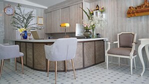 Een moderne keuken met een centraal eiland, twee barkrukken, een decoratieve stoel en een klok aan de muur.
