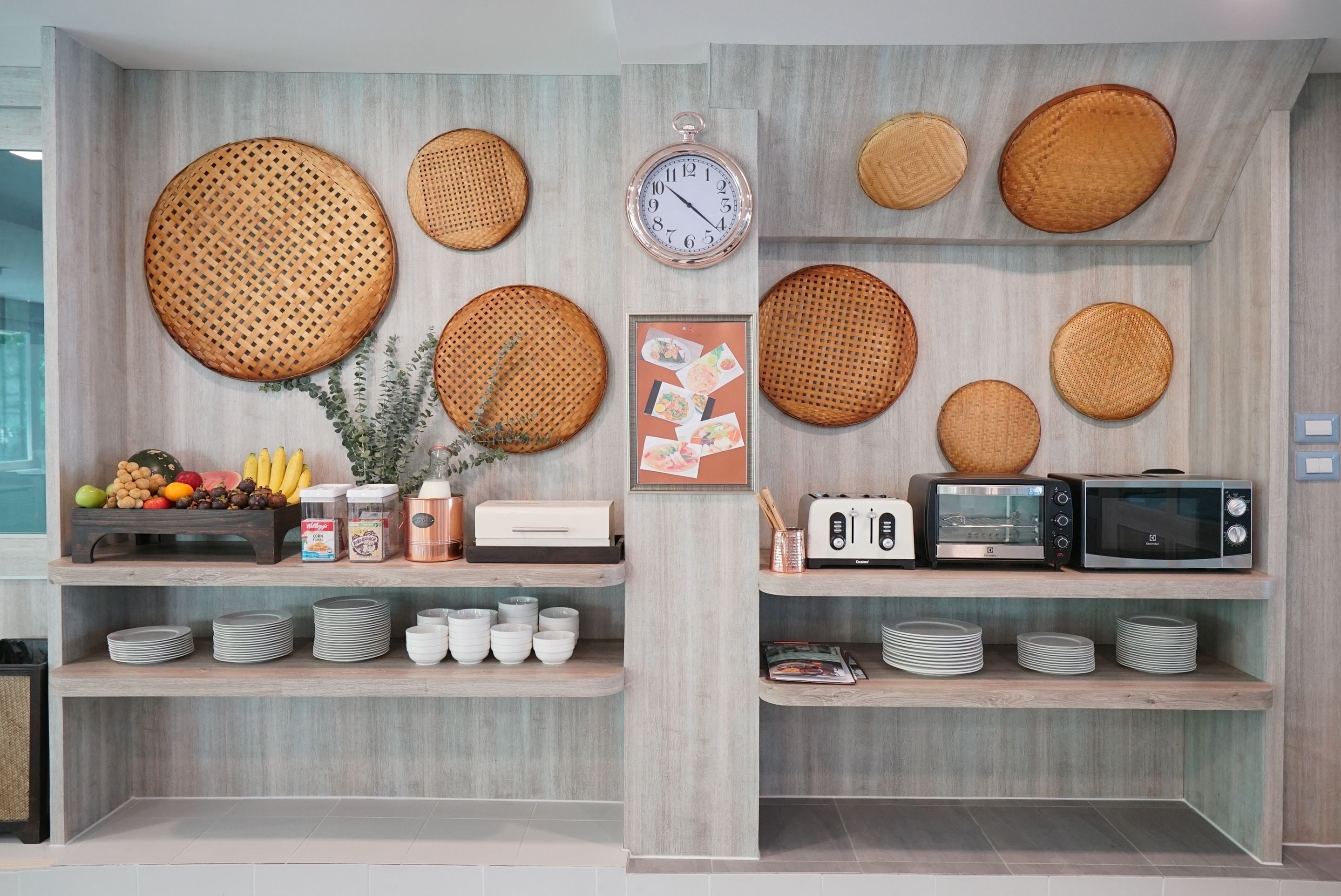 Una cocina con estantes de madera, un reloj y diversos electrodomésticos.