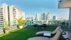 Een dakterras met kunstgras, twee lounge stoelen, een klein tafeltje en plantenpotten.