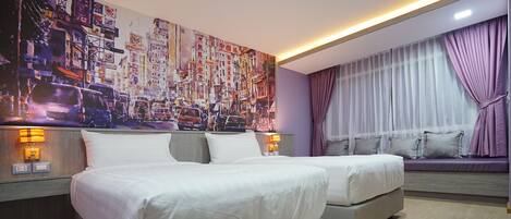 Quarto de hotel com duas camas, um mural grande com vista para a cidade na parede, uma janela com cortinas roxas e um banco embutido com almofadas.