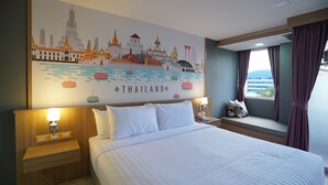 Hotelkamer met een grote muurschildering van Thailand, een bed met witte lakens, twee nachtkastjes met lampen en een raam met gordijnen.