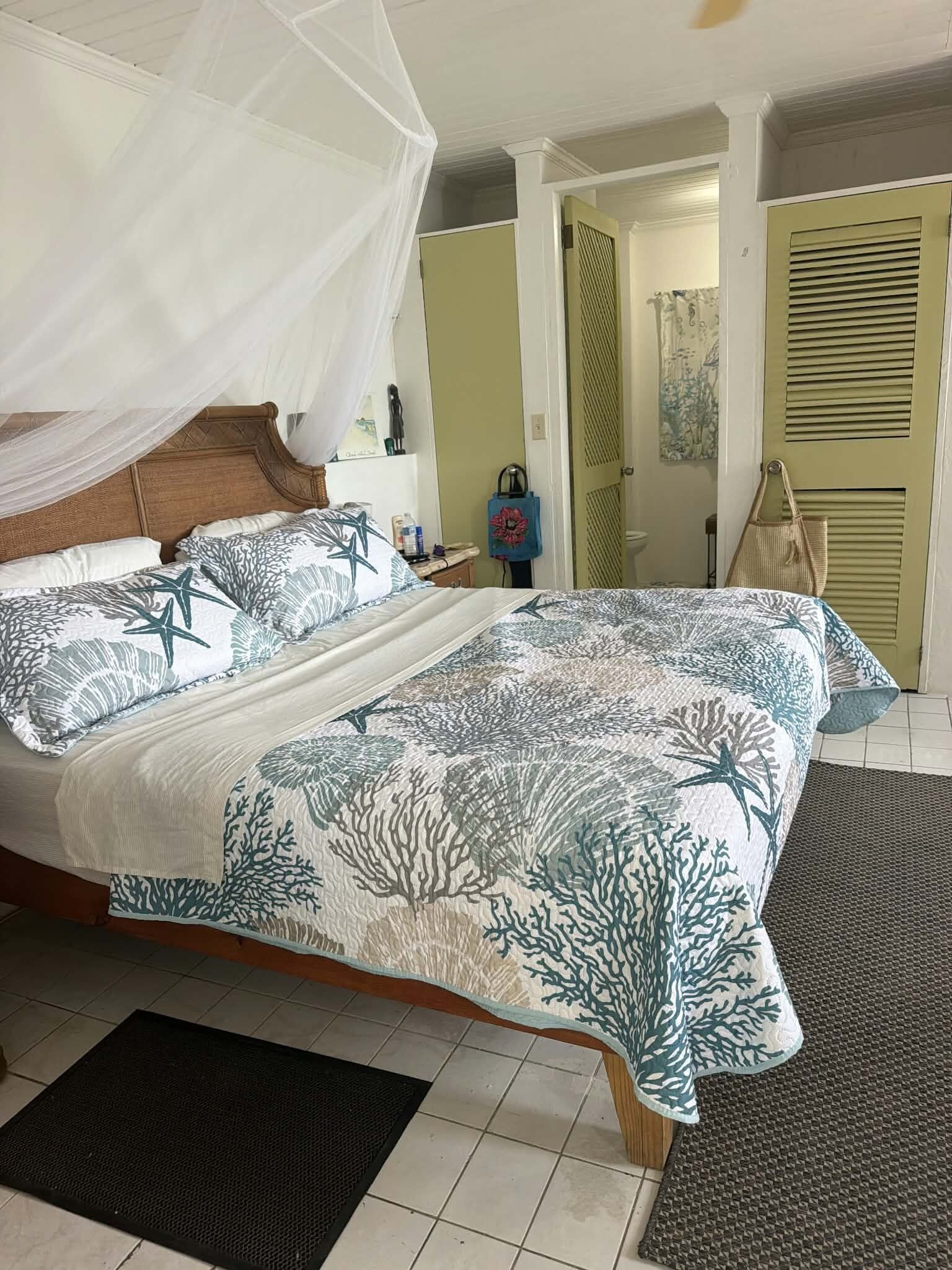 Une chambre à coucher comprenant un lit, une table de chevet, une commode, une chaise, une porte et une fenêtre.