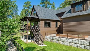 Eine zweistöckige Holzhütte mit überdachter Veranda und einer Steinmauer.