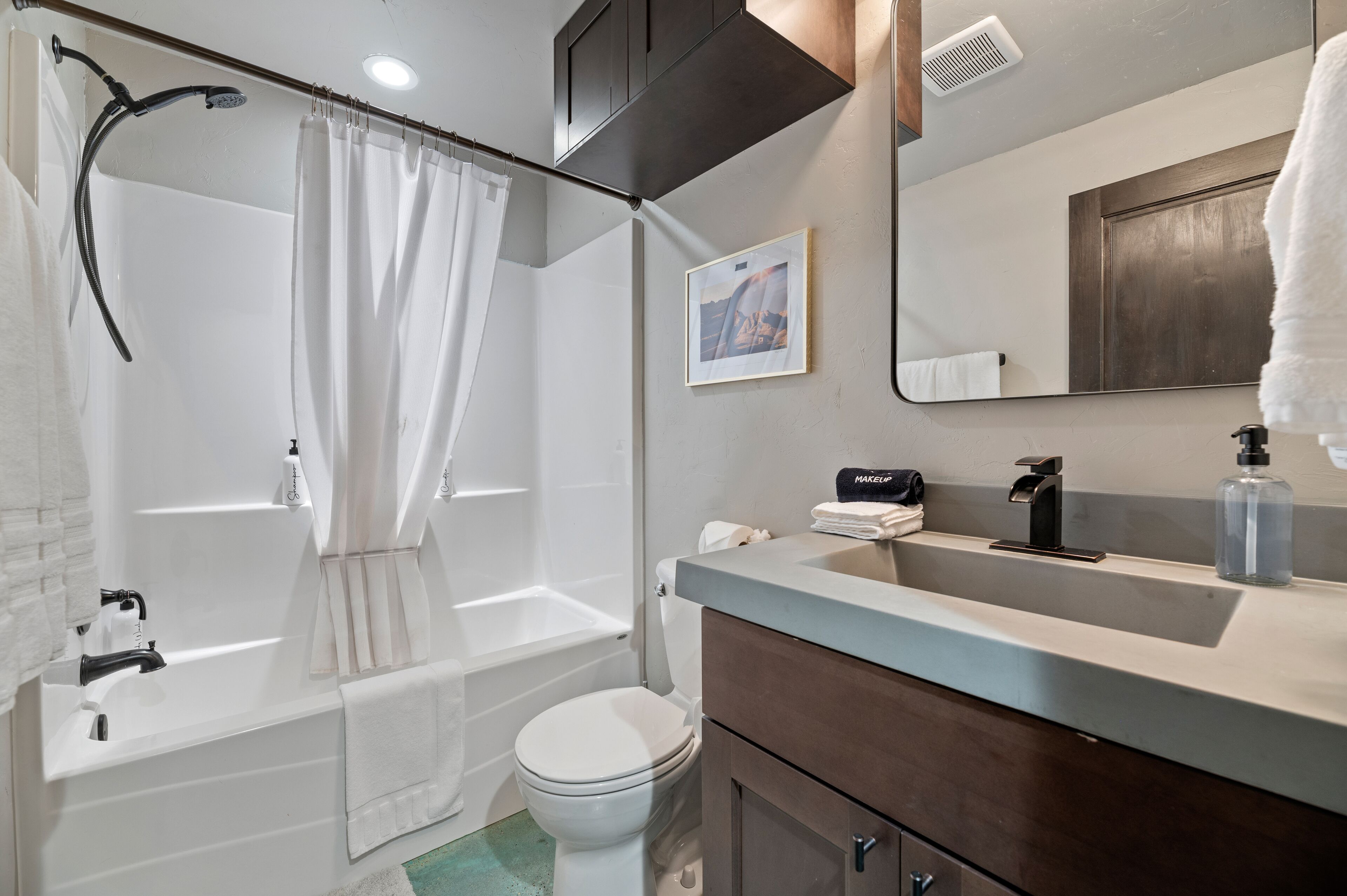 A modern bathroom with a bathtub, toilet, and vanity.