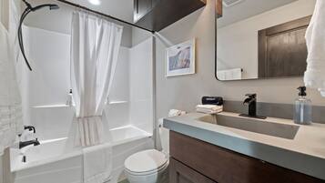 A modern bathroom with a bathtub, toilet, and vanity.