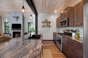 A modern kitchen with a marble countertop, built-in oven, and wooden cabinets.