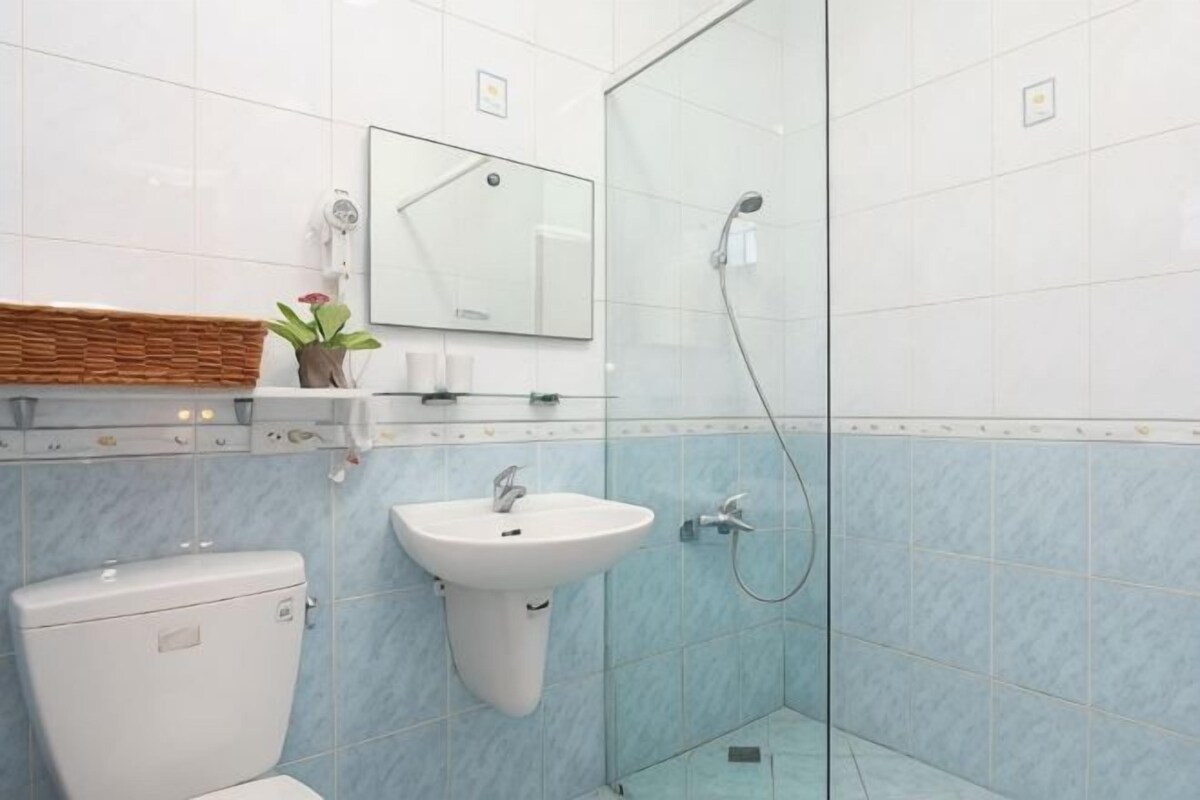 A bathroom with a toilet, sink, and glass shower enclosure.