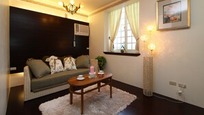 Een woonkamer met een bank, een salontafel, een vloerlamp en een schilderij aan de muur.