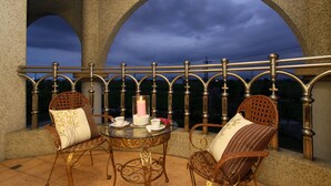 Een balkon met twee rieten stoelen, een glazen tafel en een kaars.