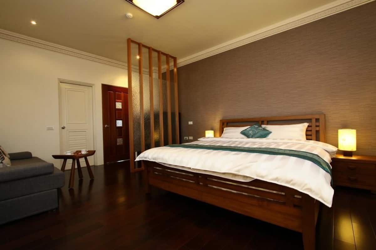 Un dormitorio con una cama de madera, lámparas de noche, una mesita y un sofá.