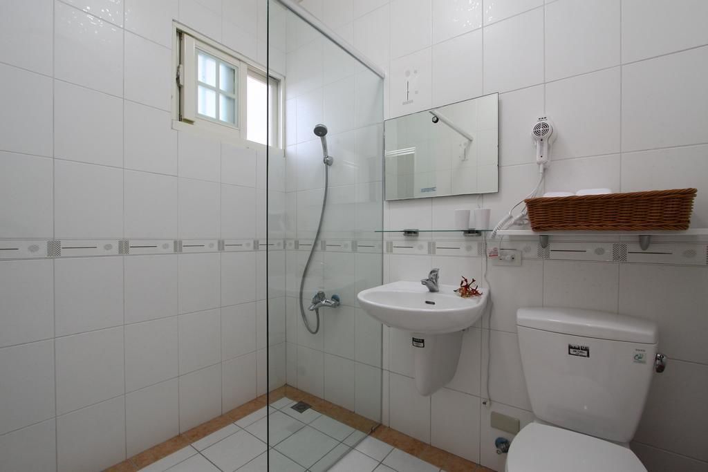 Un baño con cabina de ducha de vidrio, un lavamanos blanco, un inodoro y un espejo sobre el lavamanos.