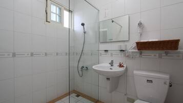 Un baño con cabina de ducha de vidrio, un lavamanos blanco, un inodoro y un espejo sobre el lavamanos.
