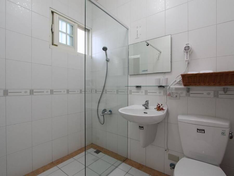 Un baño con cabina de ducha de vidrio, un lavamanos blanco, un inodoro y un espejo sobre el lavamanos.