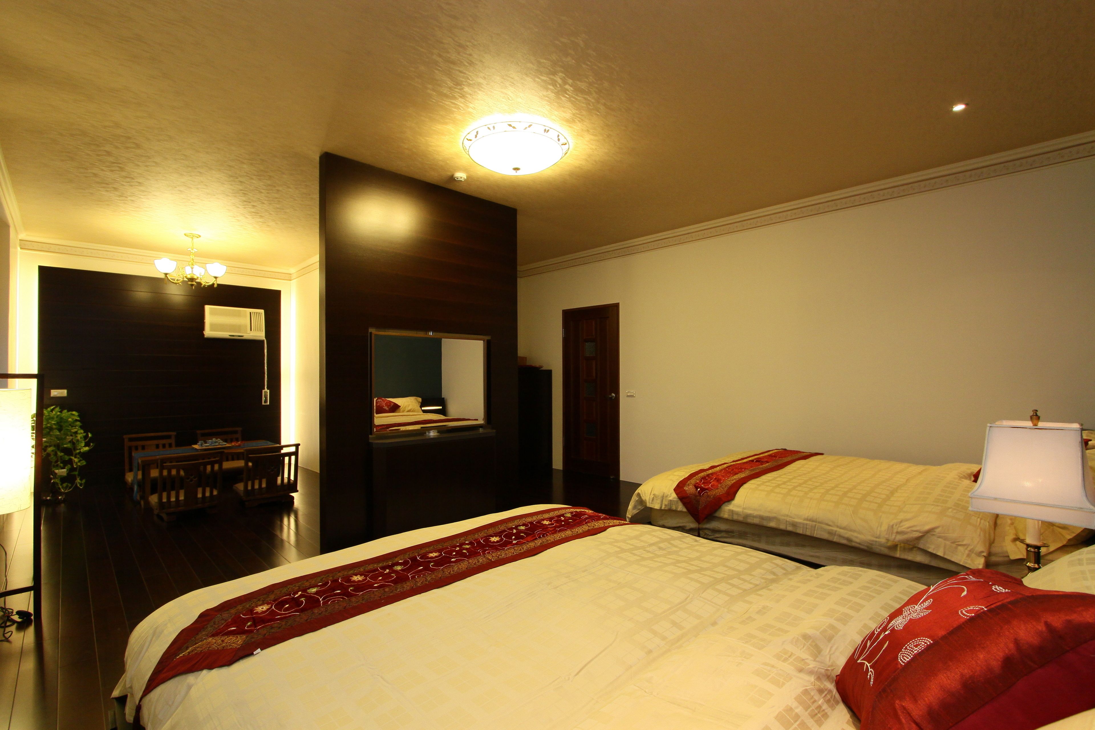 Habitación de hotel con dos camas, un escritorio, una silla, un espejo y una lámpara en el techo.