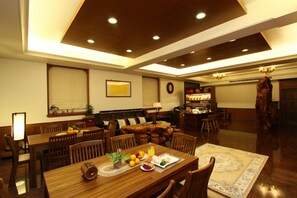 A spacious dining area with wooden furniture, a large dining table, and a cozy seating arrangement. - Star Shine B&B (Jiaoxi)