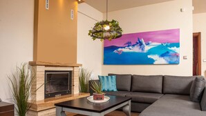 Un salon avec une cheminée, un canapé, une table basse et un grand tableau accroché au mur.