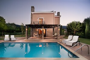 A poolside area with a pool, lounge chairs, and a covered seating area.