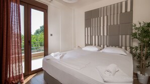Une chambre d’hôtel avec un grand lit, une vue sur la verdure par la fenêtre et une plante en pot sur le côté.