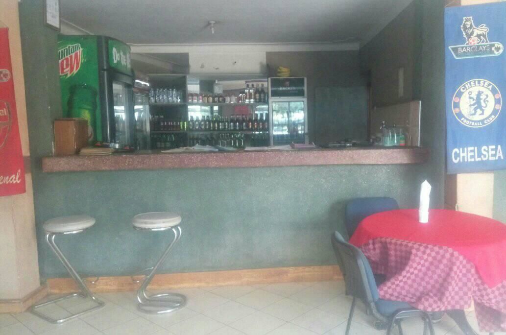 A bar area with stools, a table with a red tablecloth, and a sign for Chelsea Football Club.