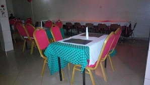 A dining area with tables covered in checkered tablecloths, surrounded by chairs with red and gold upholstery. - Kabz Hotel (Kampala)