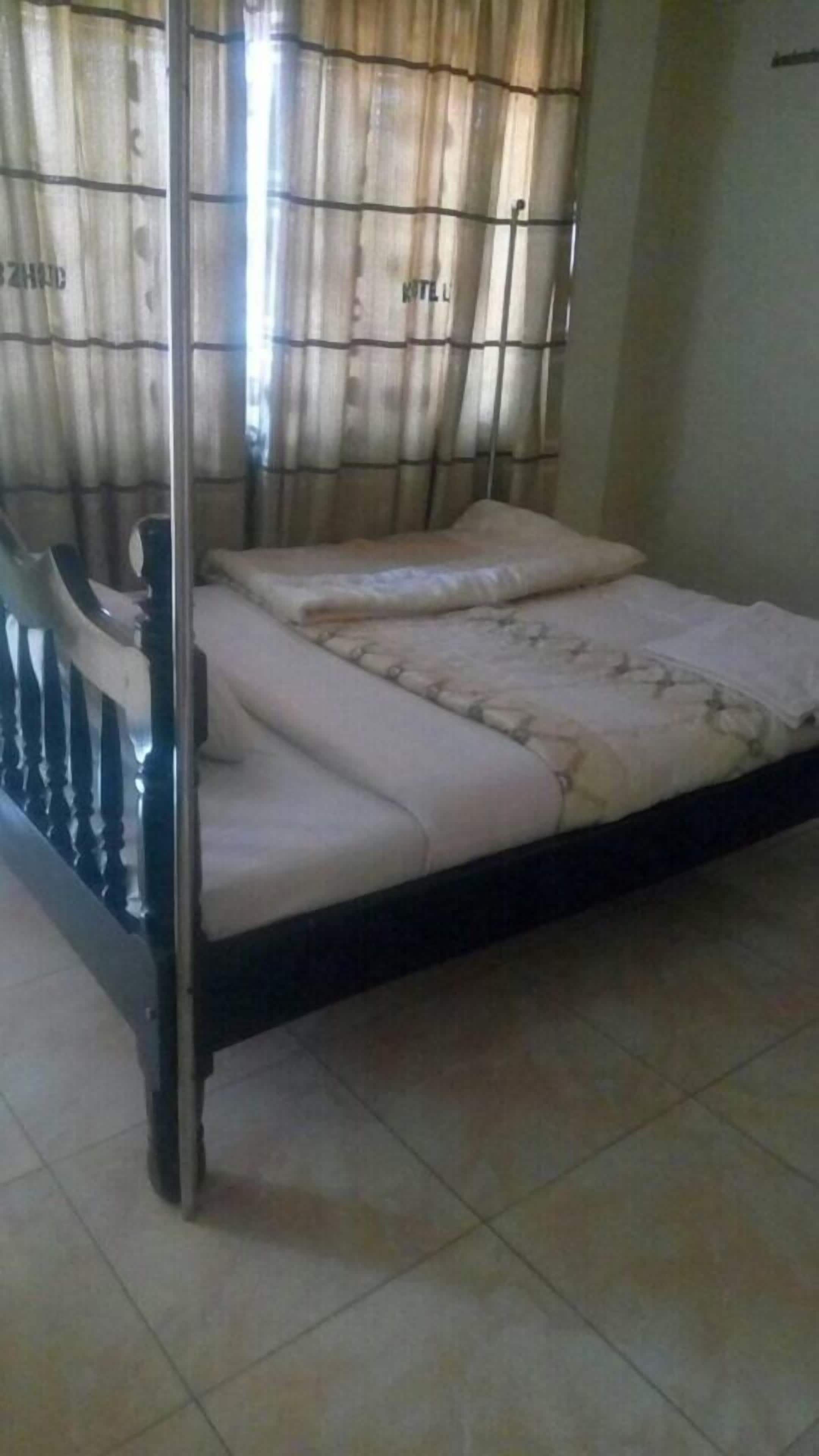 Un lit simple avec une tête de lit en bois et un matelas recouvert d’un tissu à motifs.