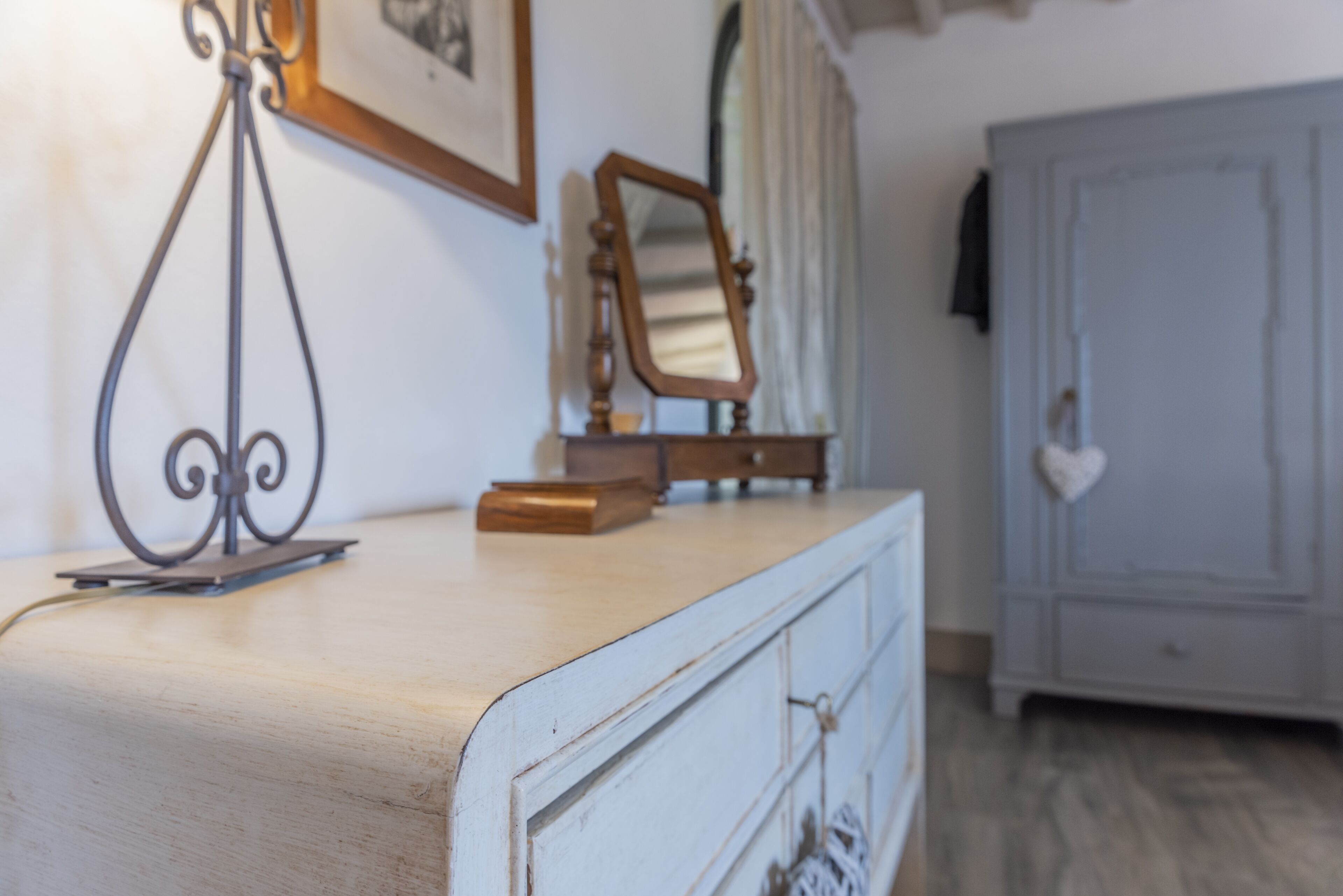 A room with a wooden dresser, a mirror, and a wardrobe.