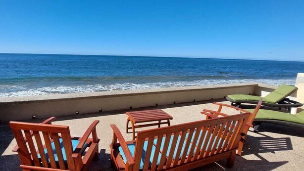 A terrace with wooden furniture and a view of the ocean. - Beautiful Private Beachfront Villa (Nuevo Mazatlan)