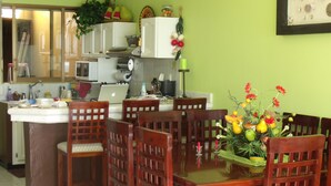 A dining area with wooden chairs and a table set for four. A vase with flowers is on the table. - Beautiful Private Beachfront Villa (Nuevo Mazatlan)