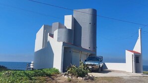 A modern building with a unique architectural design, featuring a prominent cylindrical tower and a small adjacent structure with a red roof. - Beautiful Private Beachfront Villa (Nuevo Mazatlan)