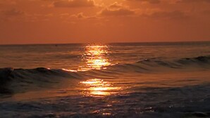 Um pôr do sol sobre o oceano, com ondas refletindo a luz do sol.